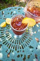 tall glass of ice tea with lemon in outdoor summer garden photo