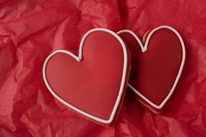 Red Heart-shaped cookies with icing detail on red background photo