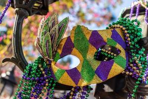 Outdoor Mardi Gras beads and mask on light post in sunshine photo