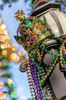 Outdoor Mardi Gras Crown and beads on light post in sunshine photo