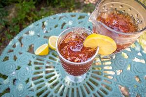 tall glass of ice tea with lemon in outdoor summer garden photo