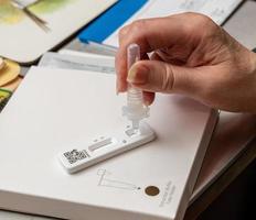 Self-test kit for Covid-19 with buffer solution being dripped onto test strip photo