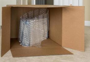 Small product wrapped in plastic wrap inside very large cardboard shipping box photo