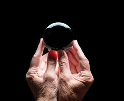 Hands holding a crystal glass forecasting ball with black center to allow easy composites photo