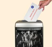 Absentee ballot or vote by mail envelope being shredded in an office shredder photo