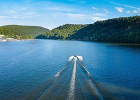 Speedboat on Cheat Lake on a summer evening with boats docked in marina photo