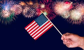 Senior man hand holding a small USA flag against fireworks background photo
