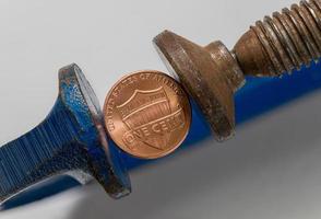 USA one cent coin being squeezed between the solid jaws of a vise or vice photo