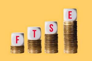 Stacks of gold coins with cubes spelling FTSE to show rise in value of the index in London photo