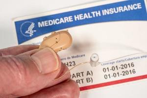 Close up of tiny modern hearing aids on medicare card background photo