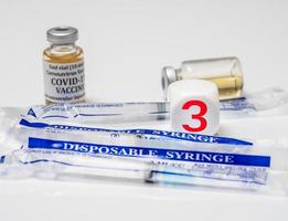 Concept for Covid-19 booster dose or shot using plasticthree block with wrapped disposable syringes photo