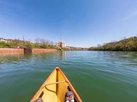 Man in small yellow pack canoe paddling down the Monongahela river in Morgantown photo