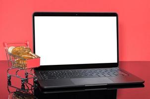 Modern laptop computer with shopping cart filled with gold coins photo