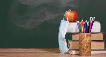 Back to virtual school background concept with stack of books and apple with face mask photo