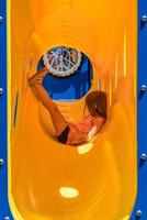 Young caucasian girl relaxing inside a yellow plastic tube on climbing frame photo