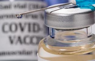 Close up of the end of the hypodermic syringe with droplet of vaccine photo