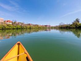 Man in small yellow pack canoe paddling up the Monongahela river in Morgantown photo