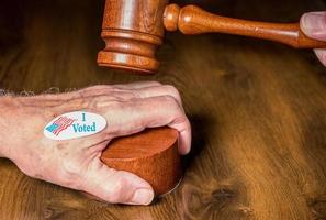 I voted campaign button or sticker on hand with a gavel and mallet to illustrate lawsuits about voting photo