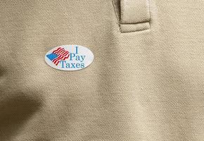 I Pay Taxes paper sticker on shirt to illustrate voter angry about rich people nto paying their share photo