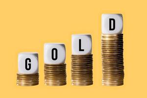 Stacks of gold coins with cubes spelling GOLD to show rise in value of the metal photo