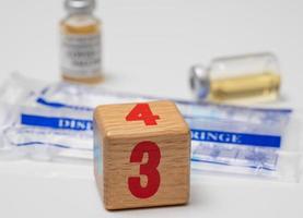 Concept for Covid-19 booster dose or shot using wooden three block with wrapped disposable syringes photo