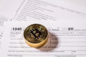 Form 1040 with bitcoin coins for reporting cyber currency gains photo