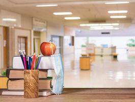 Back to school background concept with stack of books, pencil, apple with face mask photo