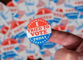 Finger with I Tried to Vote sticker in front of many election voting badges with problems getting a vote photo