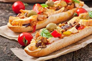 Big sandwich with roasted vegetables and chicken with cheese and basil on old wooden background photo