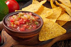 Mexican nacho chips and salsa dip in  bowl on  wooden background photo