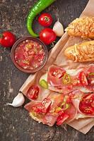 Salsa dip in bowl of bread and cheese sticks on wooden background photo