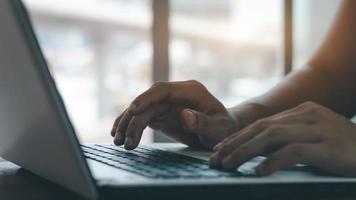 young man using laptop computer and mobile phone When looking for financial information in business, work at the desk. Writing with a pen, studying remotely from home and working from home. photo