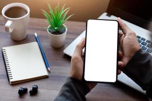 mockup copy space phone, man's hand holding smartphone with blank white copy screen for your advertising and message or information content, mobile on desk at coffee shop. photo