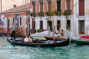 VENICE, ITALY, 2006. Gondolier Ferrying Passengers along a Canal photo