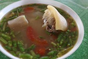 Ox's tail soup in white bowl, source soup and green background, Thailand. photo