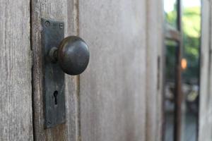 Black old door knob on wooden doors, vintage style. The doors close and pale color abrasion. Beside view. photo