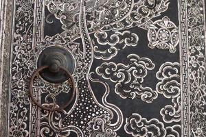 la perilla de la puerta de hierro de estilo antiguo está en la pintura tailandesa antigua puerta nativa de la iglesia, tailandia. foto