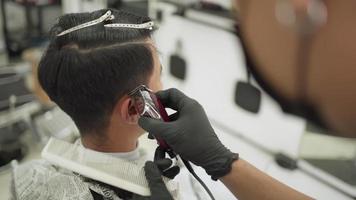 barbería de hombres asiáticos, joven cortándose el pelo en la barbería. recortando la patilla sobre el hombro, artista estilista oportunidad de trabajo peluquero profesional reabrir negocios después de una pandemia mundial video