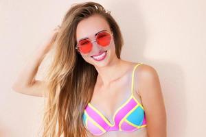 Close Up Of Happy Girl in pink sunglasses isolated. Summer holidays and fun time weekend. Summertime concept. Smiling young woman in fashion swimsuit. Selective focus. Beach Summer outfit. Copy Space photo