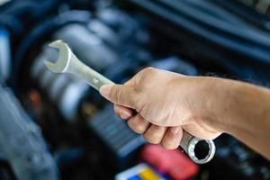 Concept of engine maintenance Mechanic holds a wrench to tighten the nut in engine repair. Engineers are examining the combustion system. Closeup. Selective focus. Blurred background. photo