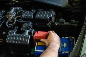 Concept of engine maintenance. Technician is checking the level of power battery. Hand of men are examining their cars' main power sources and electrical systems. DC power failed. Blurred background photo