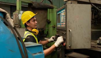 mecánico asiático trabajando en una fábrica mecánica reparando máquinas antiguas foto