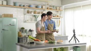 dos jóvenes blogueros amigos cercanos que preparan comida en la cocina mientras transmiten en vivo a través de un teléfono inteligente. foto