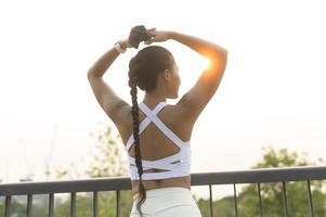 mujer joven fitness en ropa deportiva quitándose la máscara facial mientras hace ejercicio en el parque de la ciudad, la salud y los estilos de vida. foto