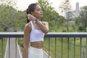 mujer joven fitness en ropa deportiva quitándose la máscara facial mientras hace ejercicio en el parque de la ciudad, la salud y los estilos de vida. foto