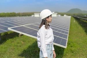 ingeniera con casco en granja de células fotovoltaicas o campo de paneles solares, energía ecológica y limpia. foto