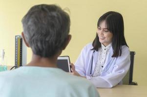 El paciente masculino asiático mayor está consultando y visitando al médico en el hospital. foto