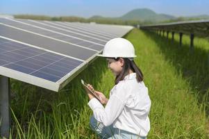 Female engineer wearing helmet in Photovoltaic Cell Farm or Solar Panels Field, eco friendly and clean energy. photo