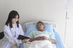 El paciente masculino asiático mayor está consultando y visitando al médico en el hospital.