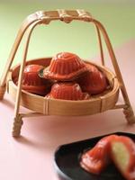 High angle view of red tortoise cakes in small bamboo basket and green and pink background. photo